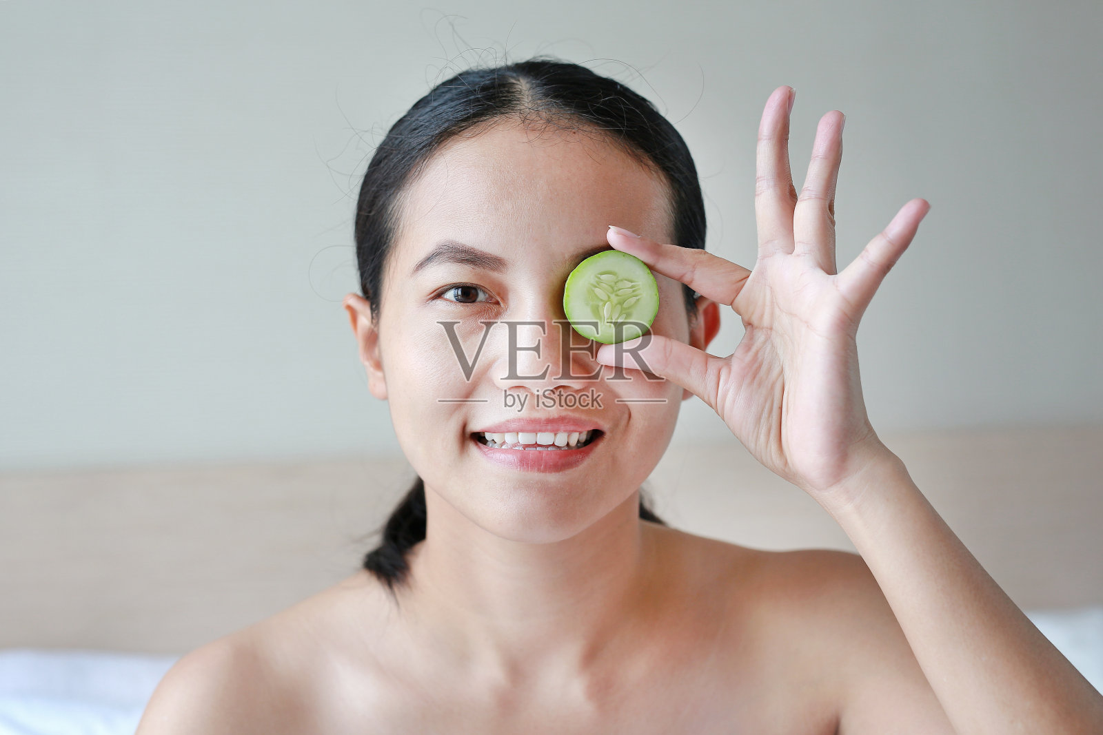 一个年轻漂亮女人的肖像，眼睛上放着黄瓜片。照片摄影图片