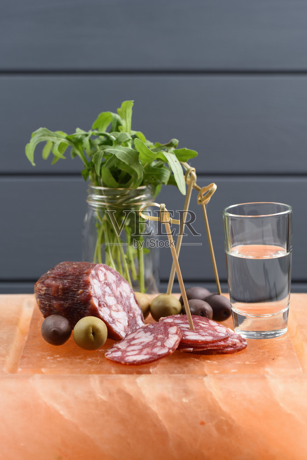 伏特加配开胃菜:烟熏腊肠、新鲜芝麻菜、绿色和calamata橄榄，配上喜马雅粉色盐块照片摄影图片