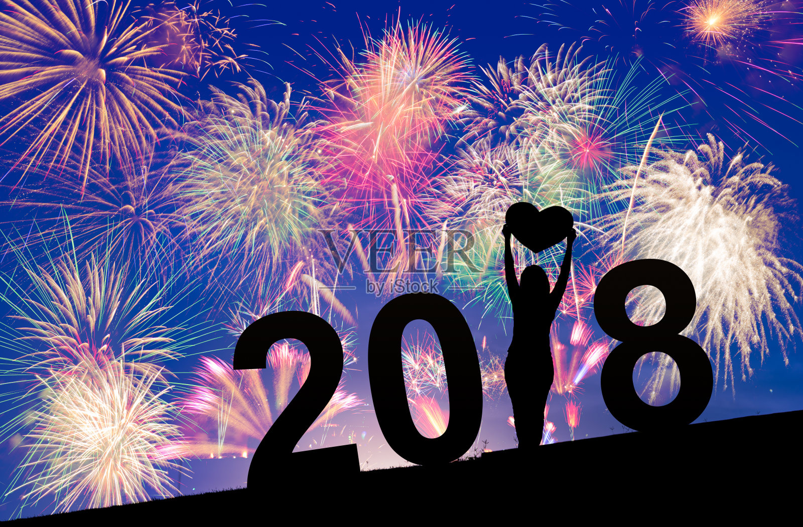 五彩缤纷的烟花在蓝色和紫色的暮色背景下，以女性剪影庆祝2018年除夕之际，节日庆祝的概念照片摄影图片