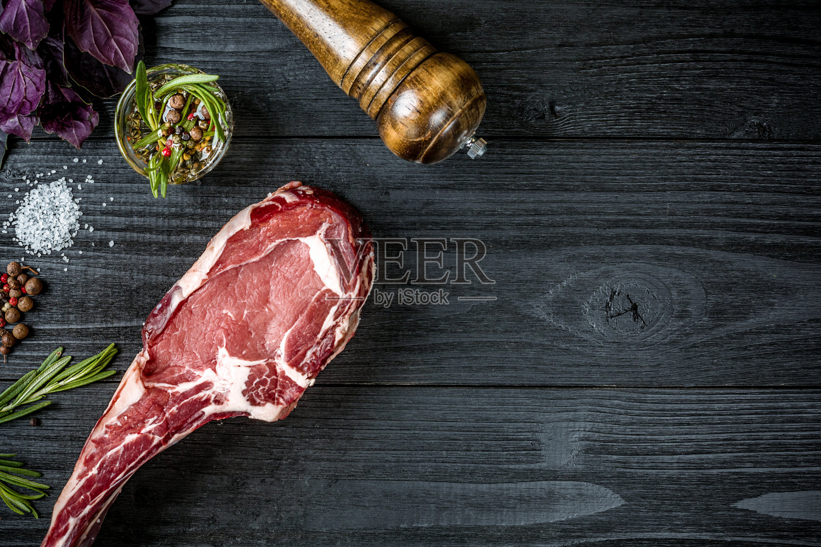 新鲜的生牛肉，罗勒和一枝迷迭香在黑色木质背景下照片摄影图片