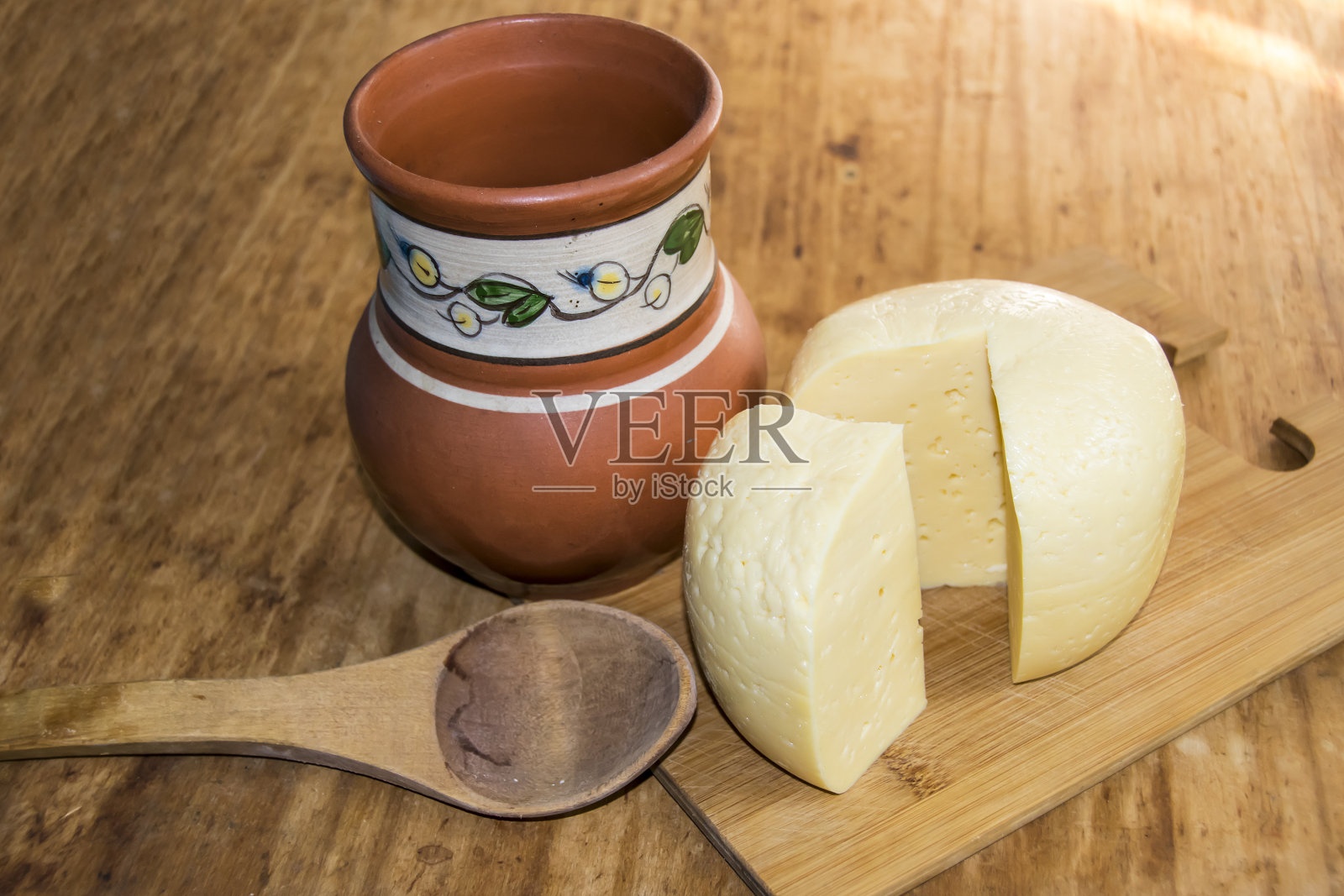 奶酪头，切成薄片，牛奶勺放在木头的背景上照片摄影图片