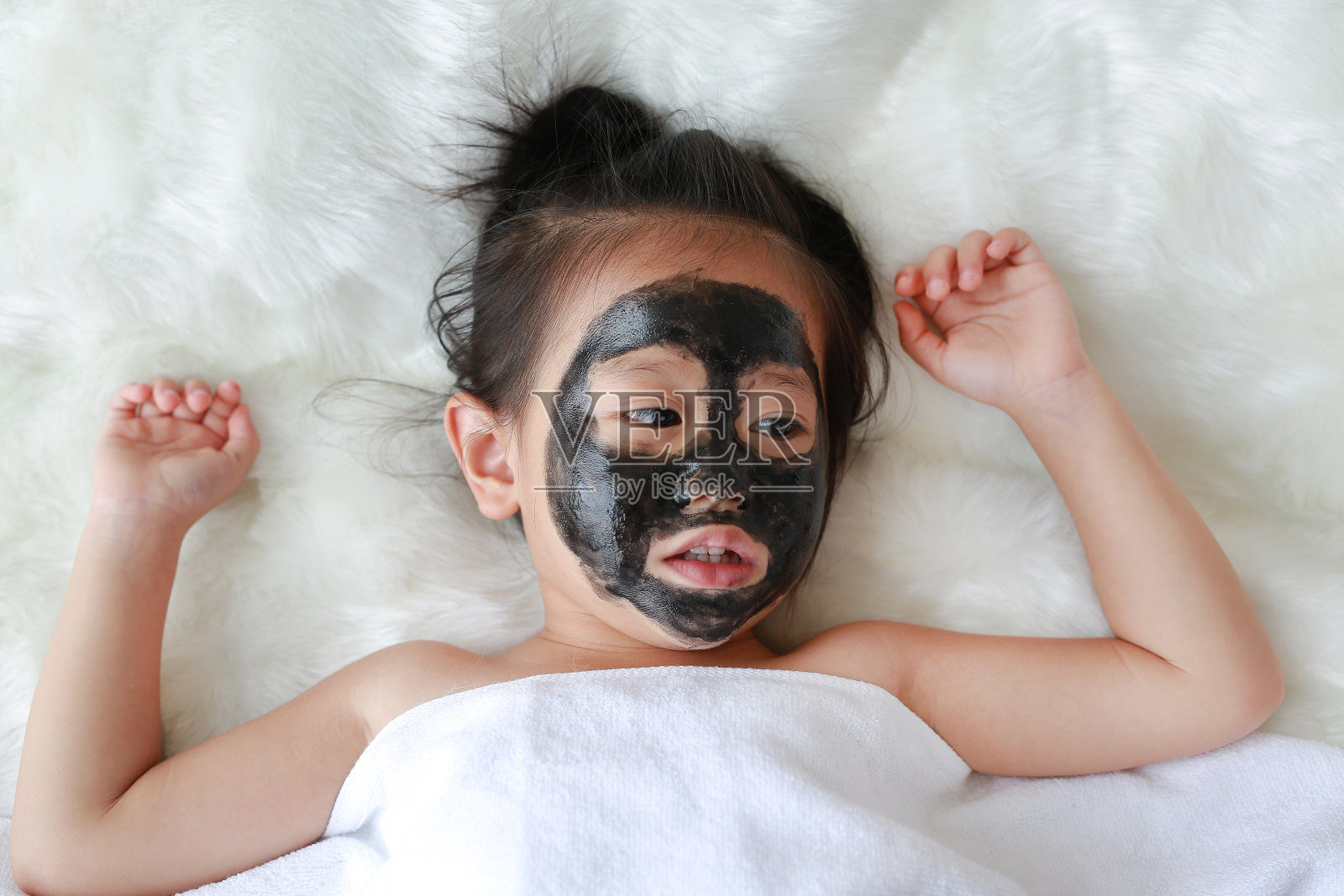 小女孩在煤剥皮面膜，美的概念。照片摄影图片