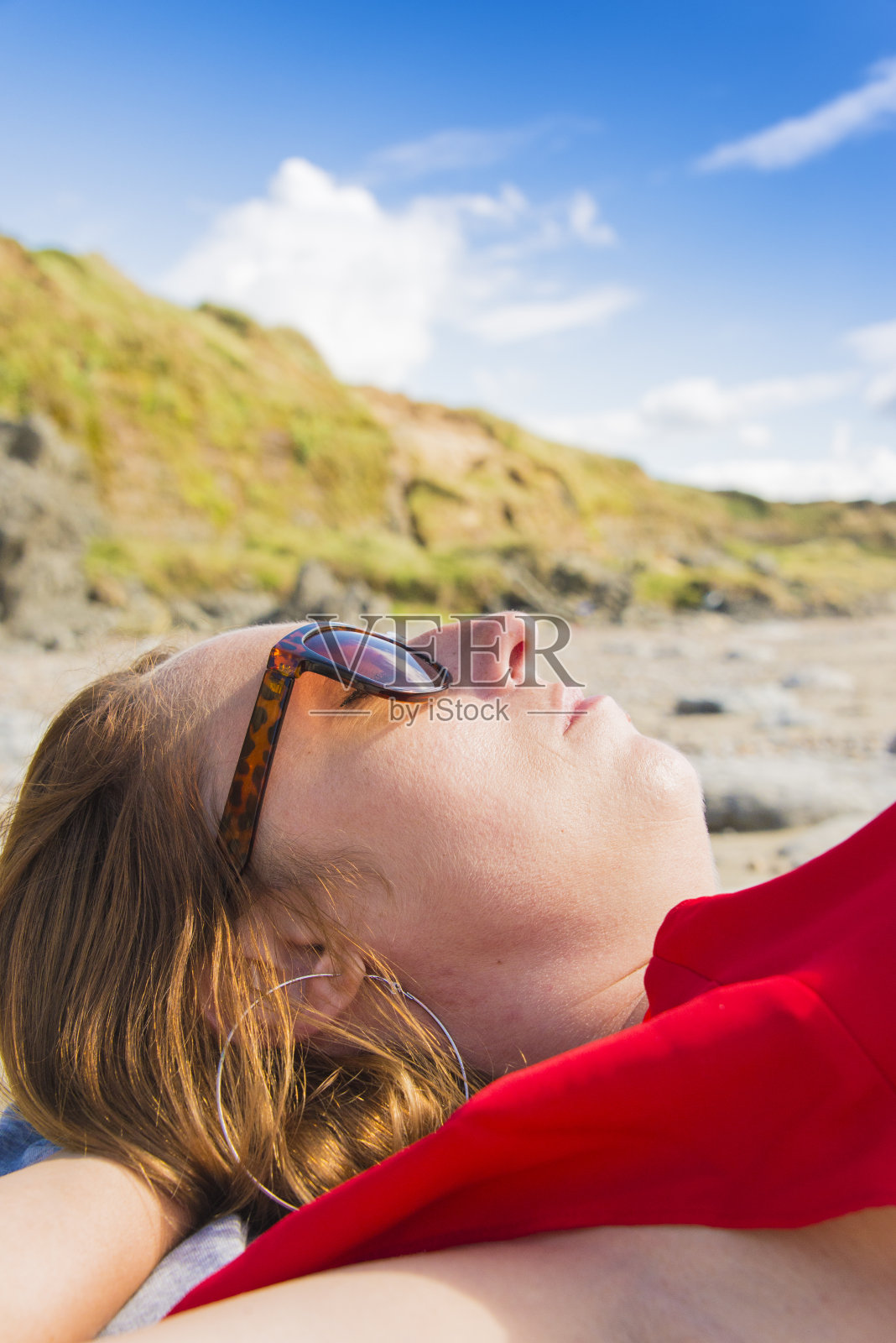 海滩上一位穿着红衣服戴着耳环的漂亮女士照片摄影图片