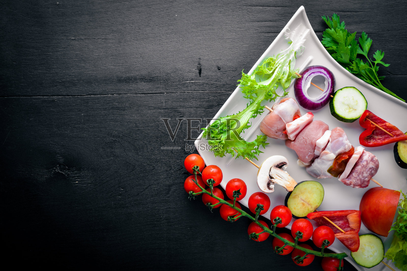 生羊肉串和新鲜蔬菜。在木制的背景上。前视图。空闲空间的文本。照片摄影图片