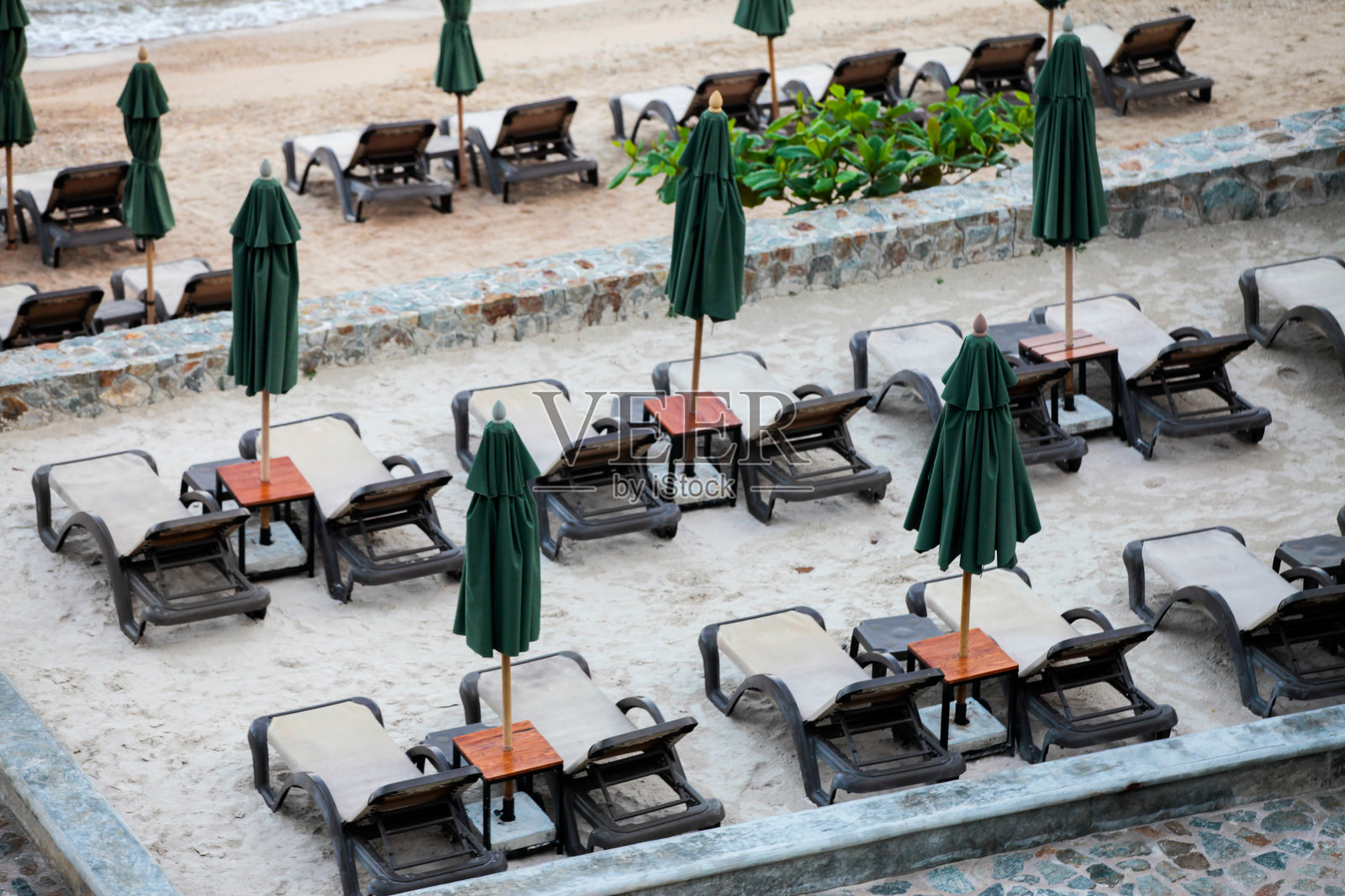 带伞的沙滩椅、沙滩上的室外游泳池。照片摄影图片