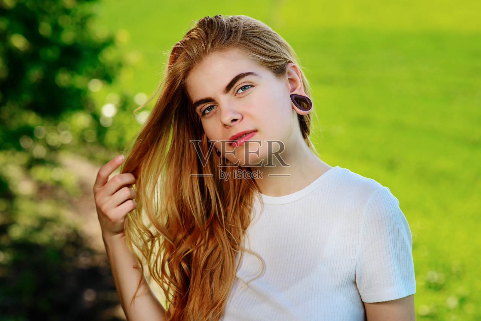 一个年轻美丽的女人的肖像，她的耳朵里有木制的隧道照片摄影图片