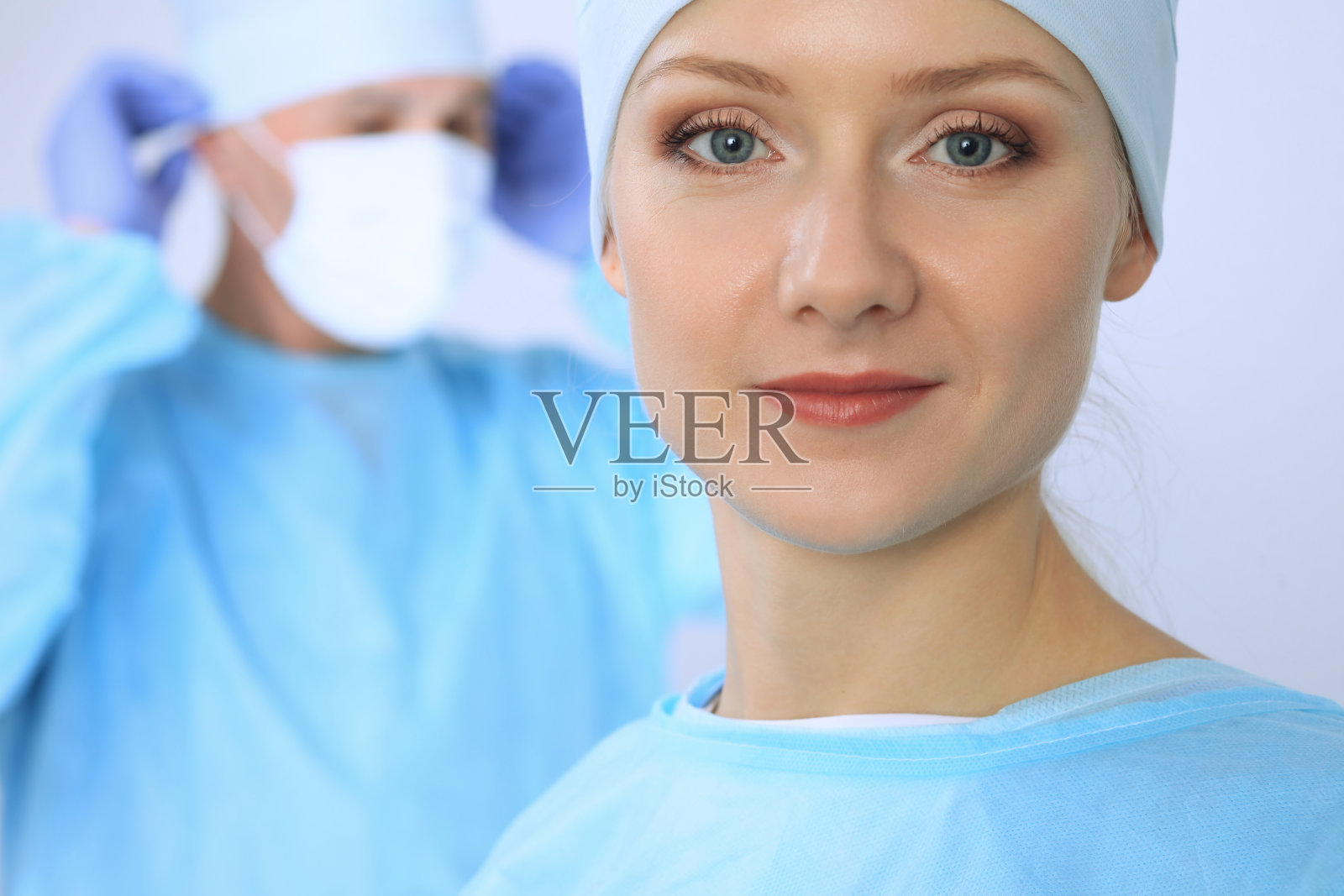 外科医生正在检查手术，而医疗队正忙着照顾病人。医疗保健和医院急诊照片摄影图片