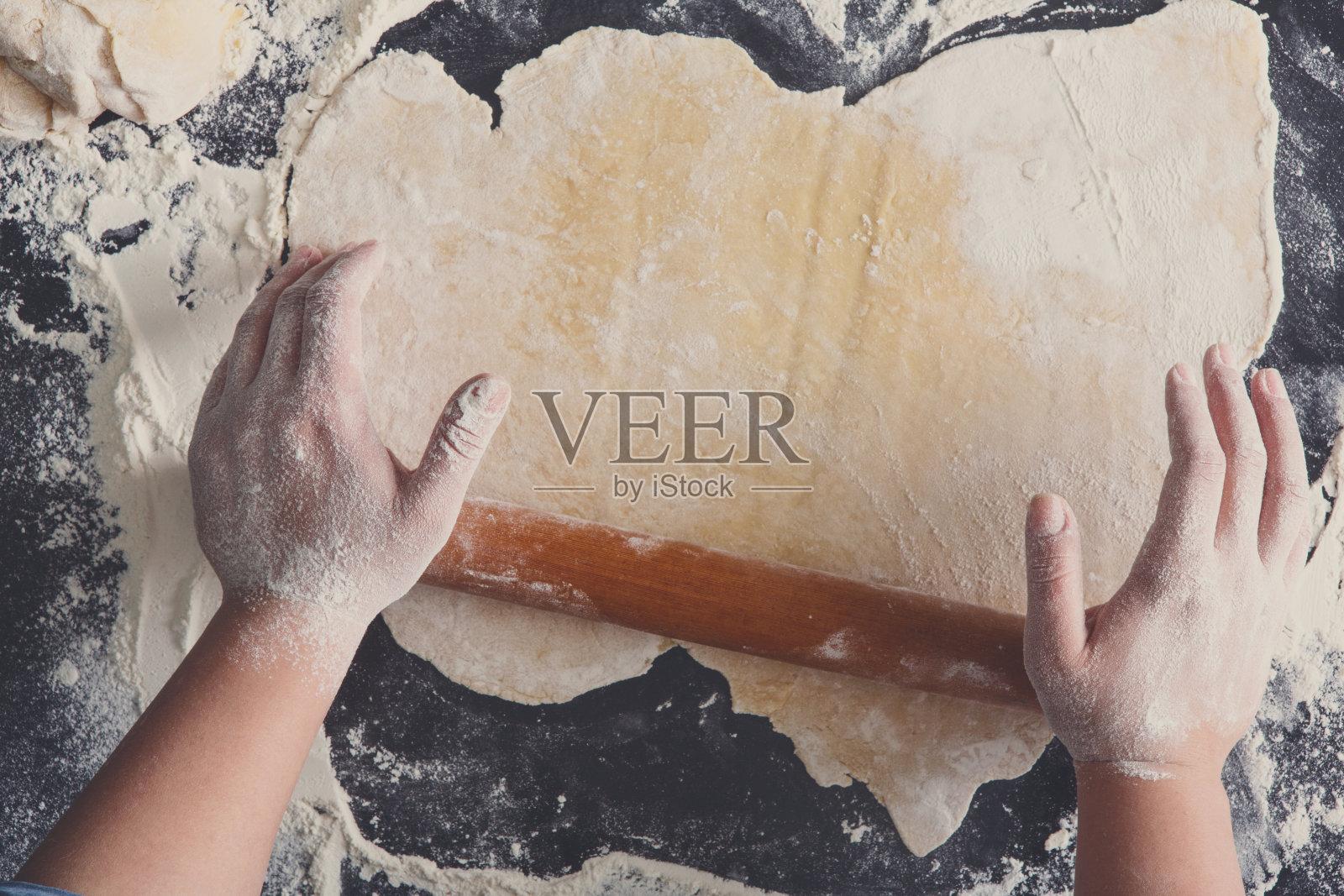 烘焙的概念。双手俯视图滚动面团在黑色背景。照片摄影图片