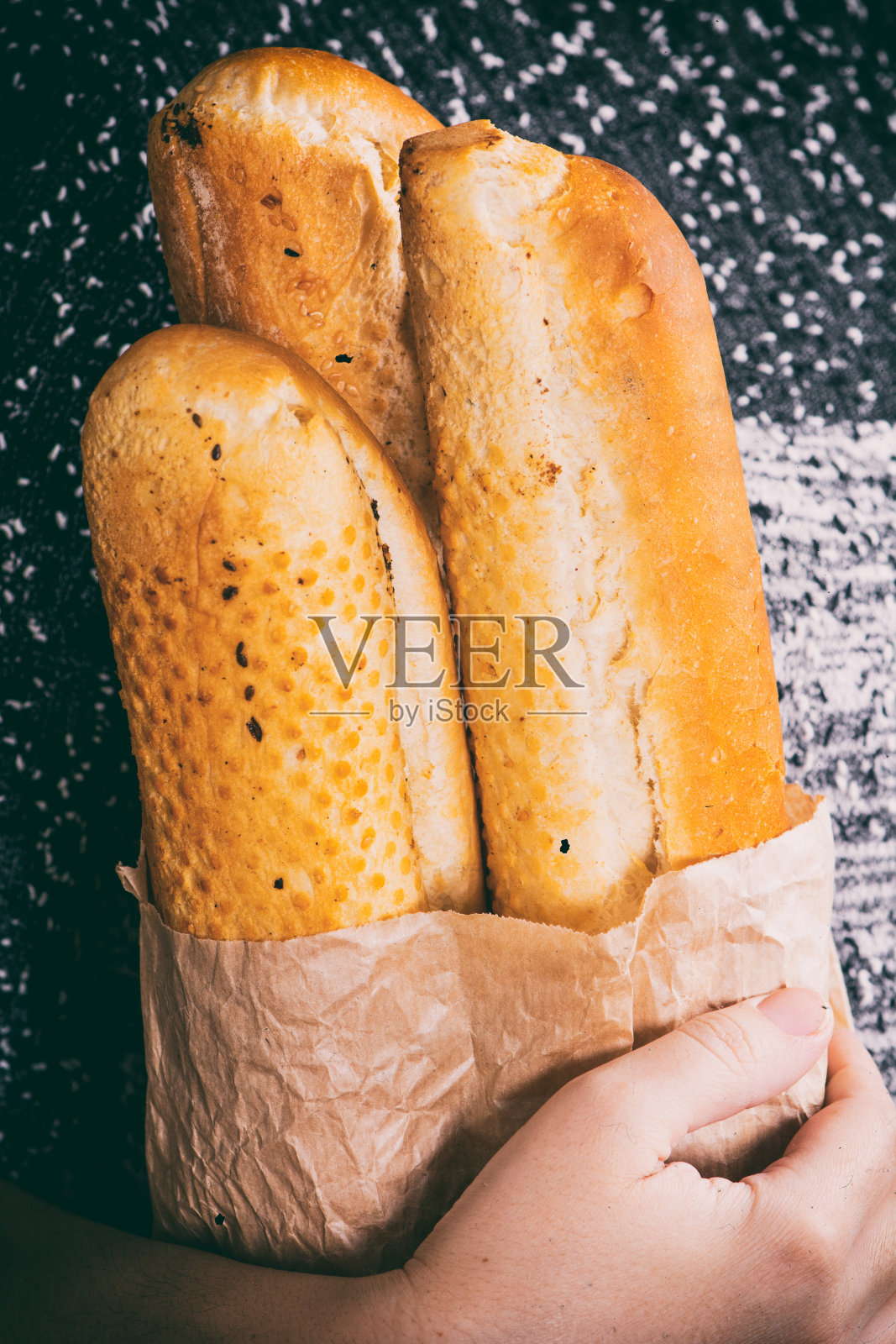 手里拿着纸袋里的长棍面包照片摄影图片