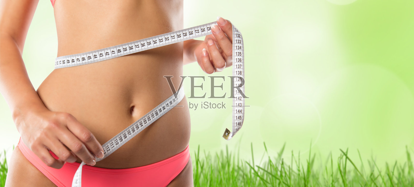 一个身材苗条的女孩在量她的腰照片摄影图片