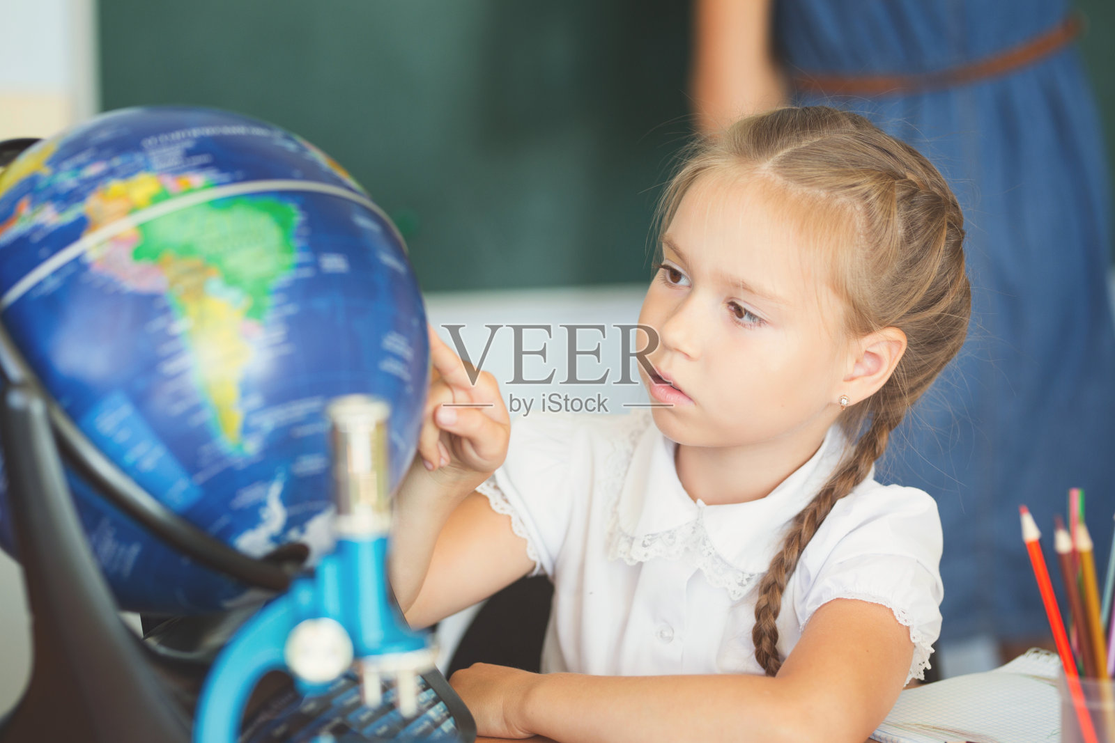 女学生在学校教室里看地球仪照片摄影图片