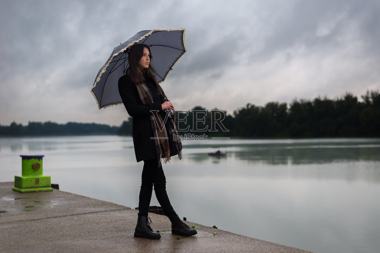 一名年轻女子在雨中撑着伞站在码头上照片摄影图片