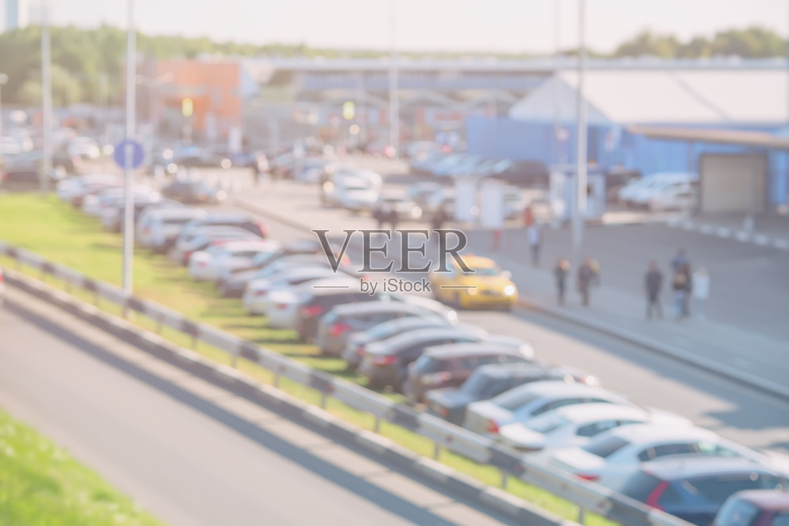 抽象模糊的景象，在阳光明媚的日子里，城市停车场上的汽车，旁边的购物中心，外面照片摄影图片