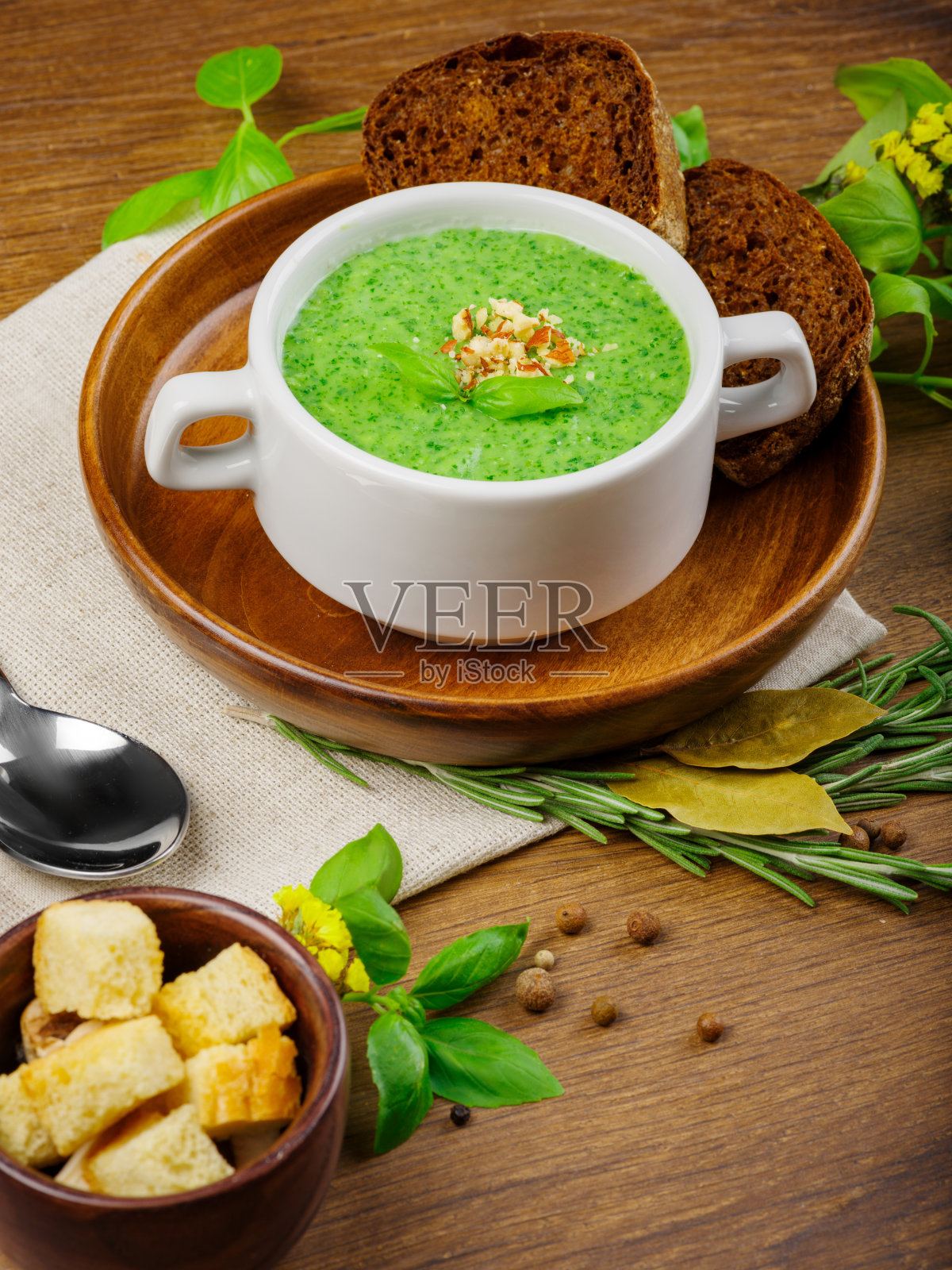 绿色蔬菜奶油汤在白色的碗与黑面包和芹菜在木背景。食品的概念。照片摄影图片