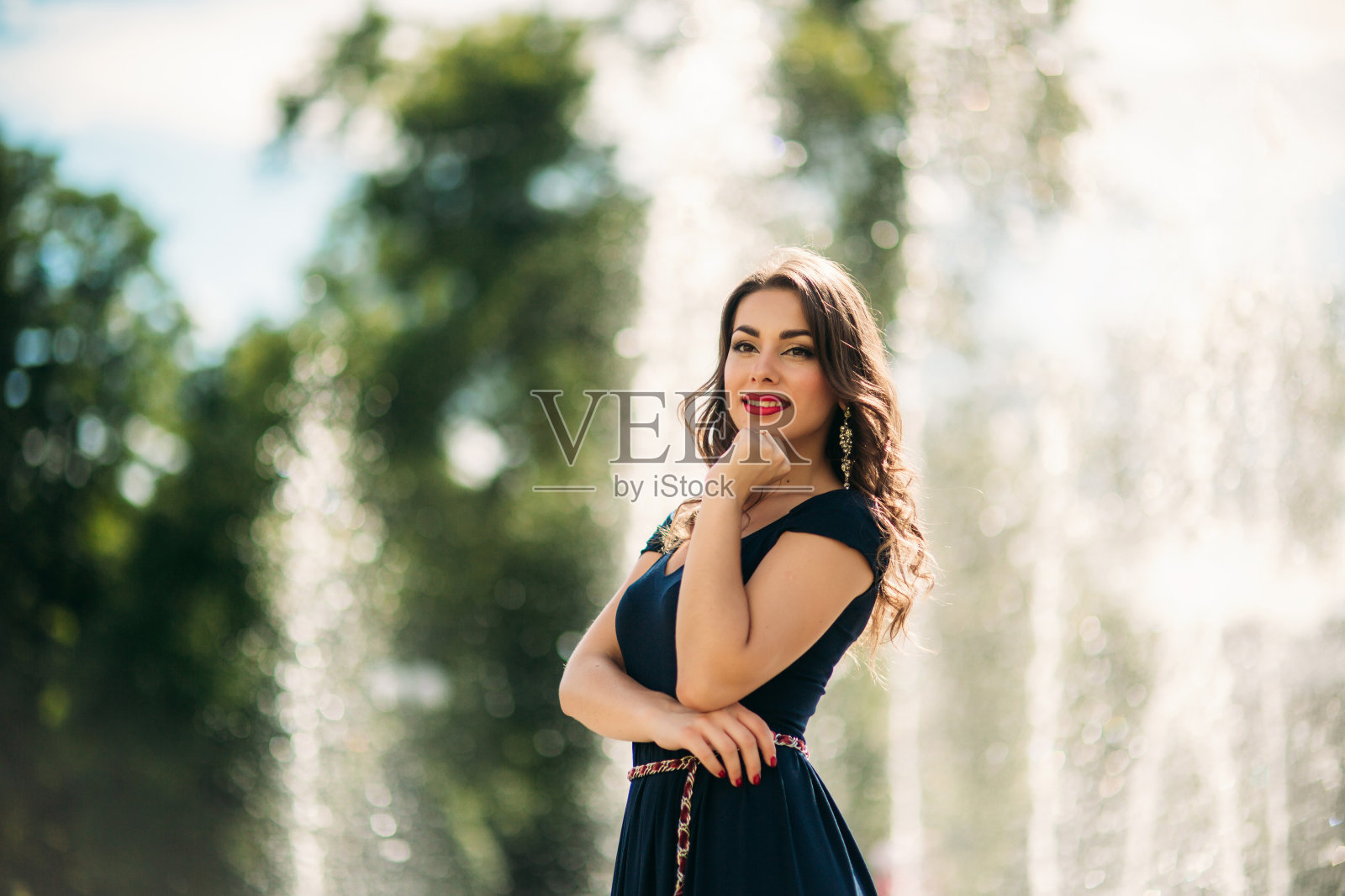 一个女孩在城市里散步，旁边是一个大喷泉。阳光明媚的一天。夏天。照片摄影图片