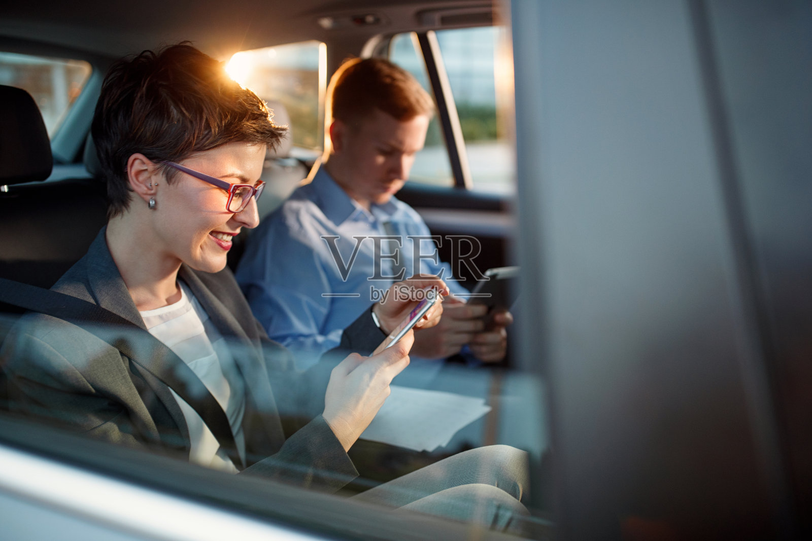 微笑的商务女性在车里打智能手机照片摄影图片