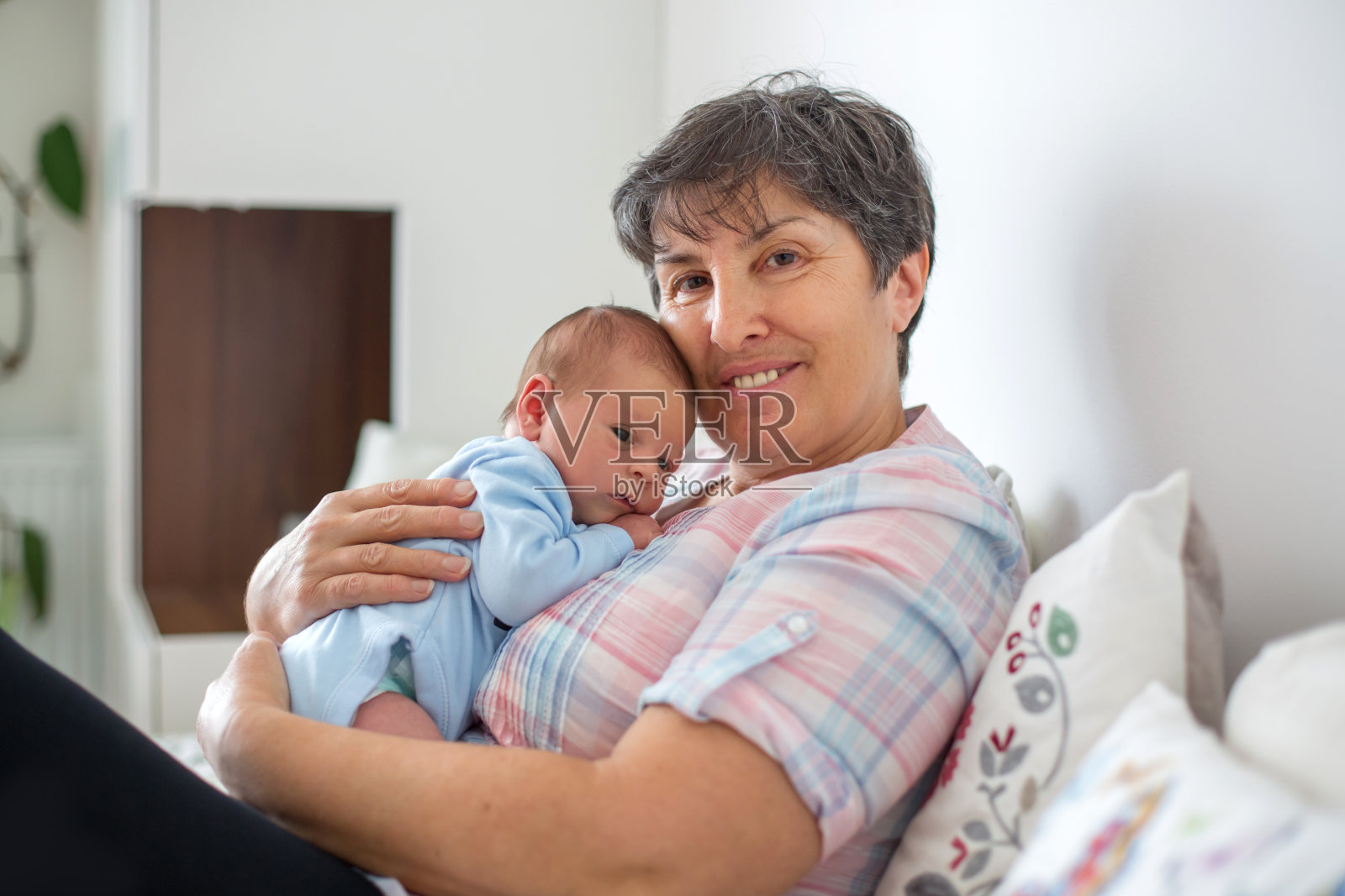 漂亮的小男孩在祖母的怀里照片摄影图片