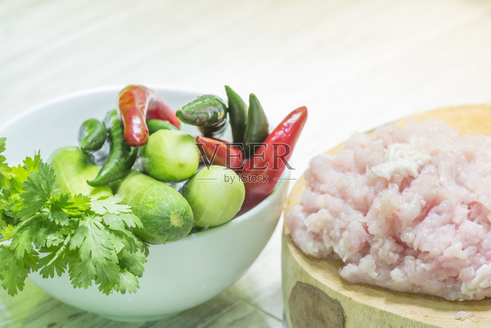 把生鸡肉放在砧板上，拌上蔬菜。照片摄影图片