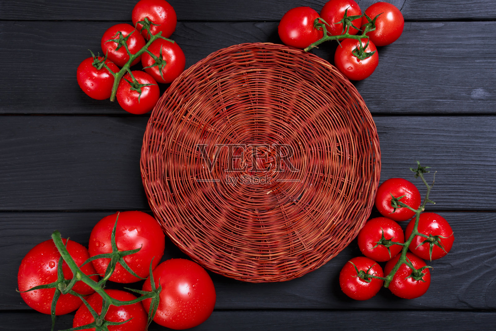 篮子周围的番茄俯视图。漂亮的一套健康，彩色的西红柿在一个木制的背景。照片摄影图片