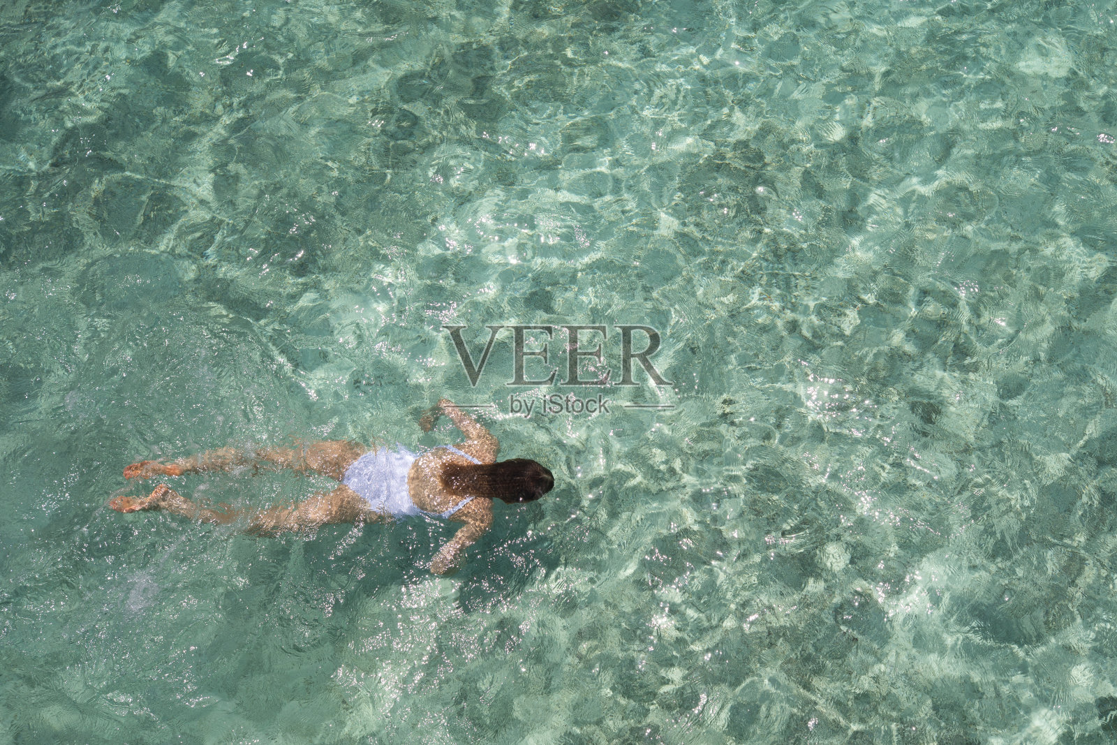 小女孩在碧绿的水中游泳。照片摄影图片