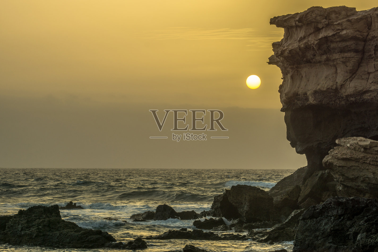 日落时海面上的一块巨石照片摄影图片