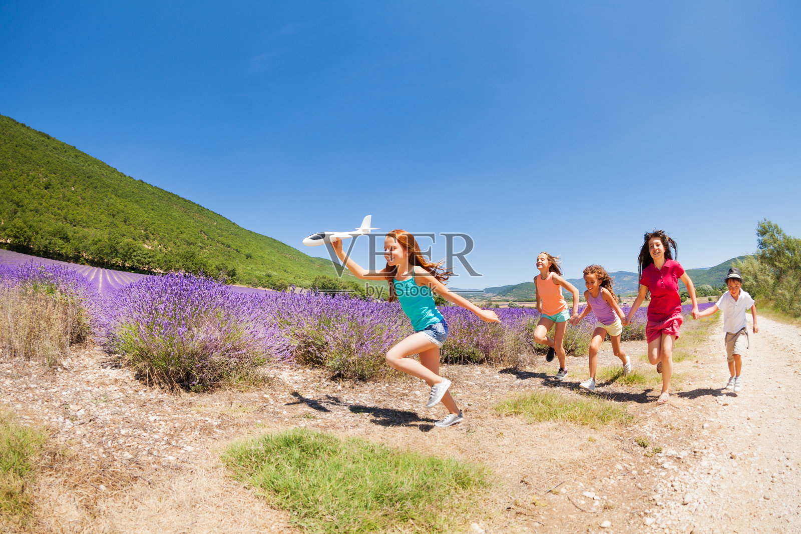 带着飞机模型跑在朋友们前面的女孩照片摄影图片
