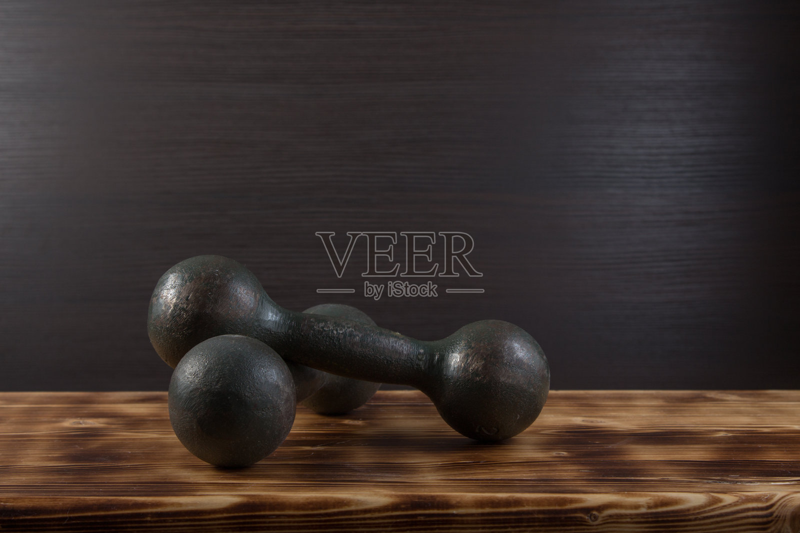 木质表面的旧哑铃。照片摄影图片
