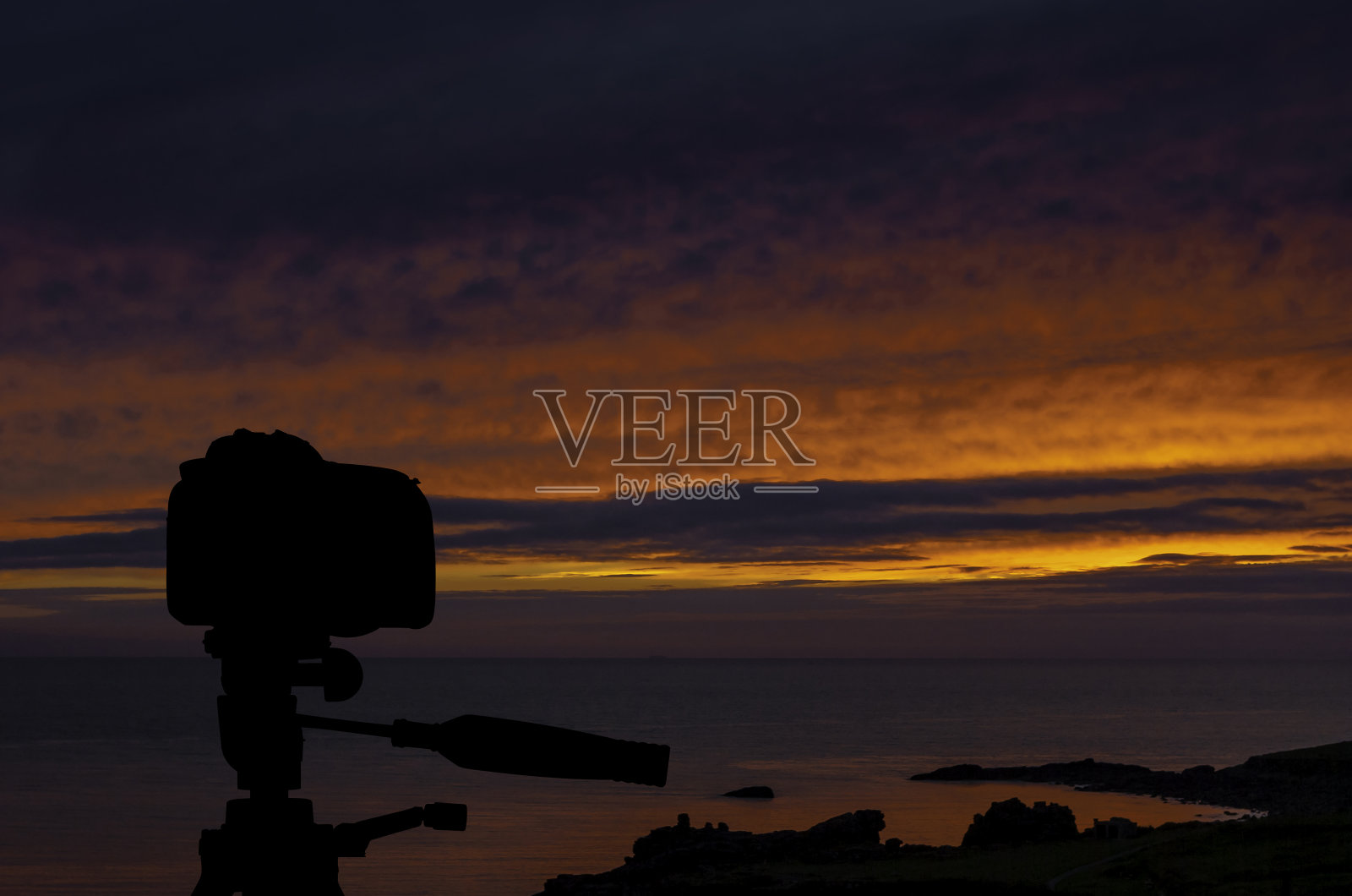 三脚架上的相机，背景是海洋和日落照片摄影图片