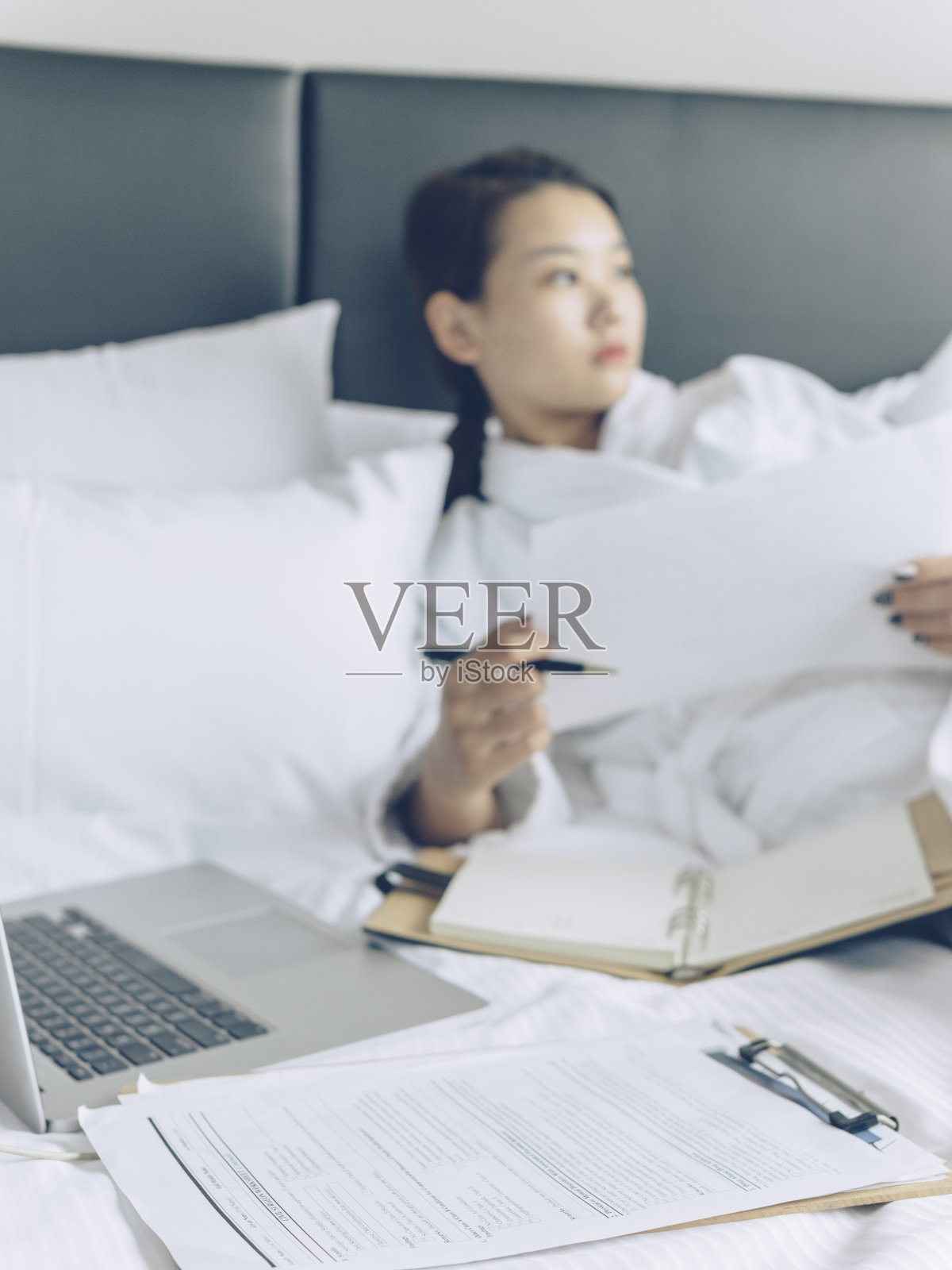 穿着浴袍的亚洲年轻女子用笔记本电脑检查文件照片摄影图片