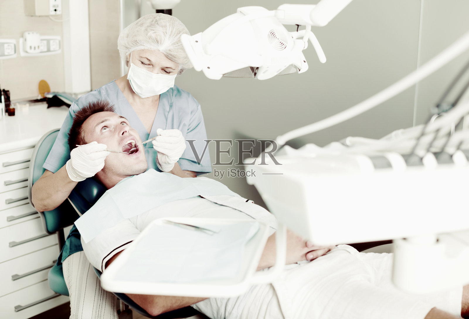 女牙医治疗男性病人照片摄影图片