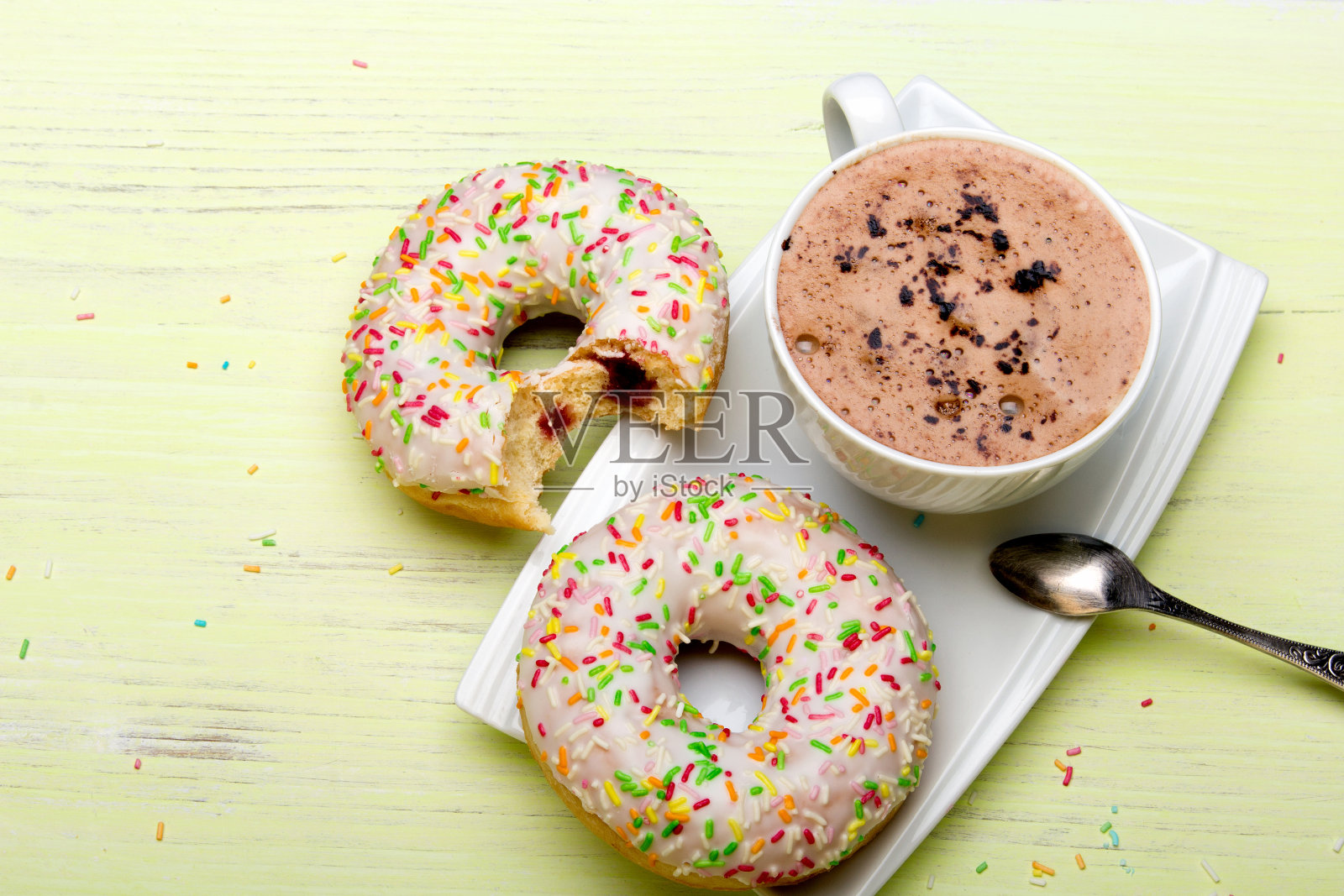 一杯咖啡和美味的甜甜圈与糖霜和巧克力在绿色的木制背景，复制空间照片摄影图片