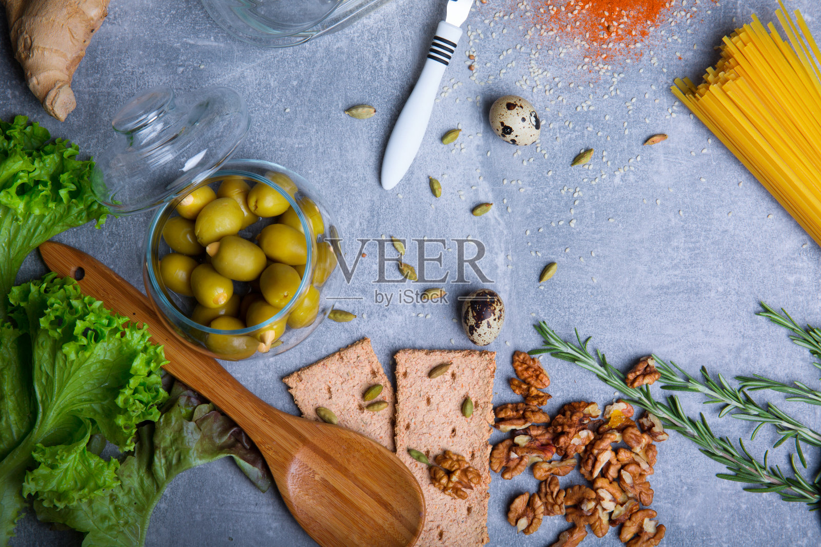 灰色背景上的核桃、面包、香料和沙拉俯视图。有机意大利面。烹饪概念。照片摄影图片