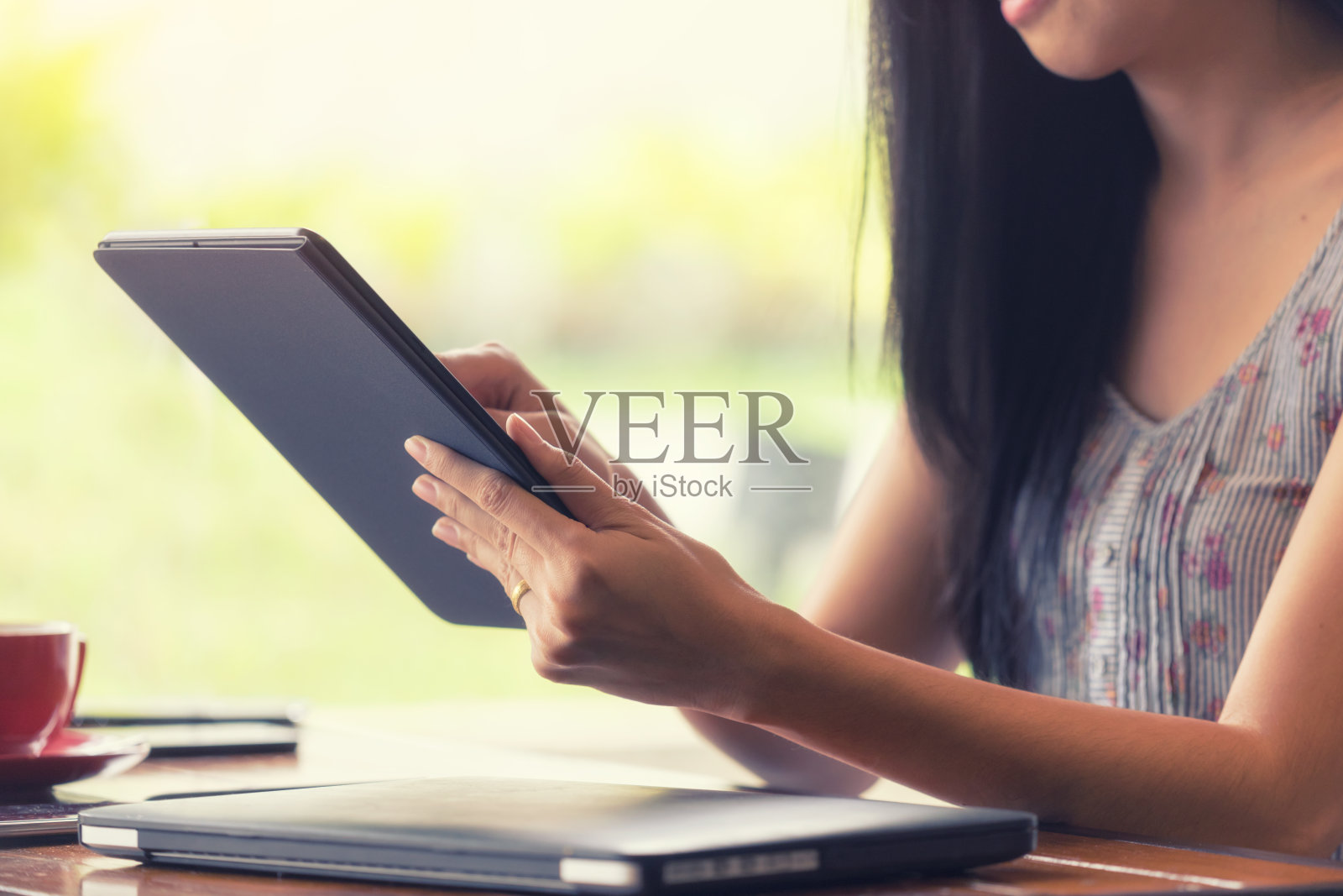 在咖啡店里用平板电脑的女人。照片摄影图片