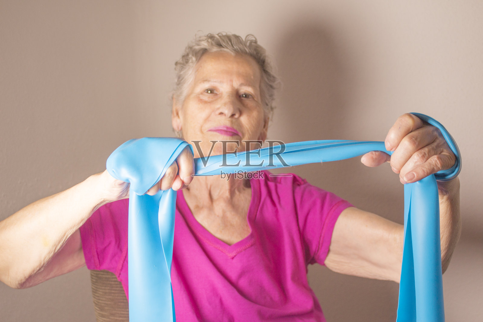 老年妇女用橡皮筋做的康复运动照片摄影图片