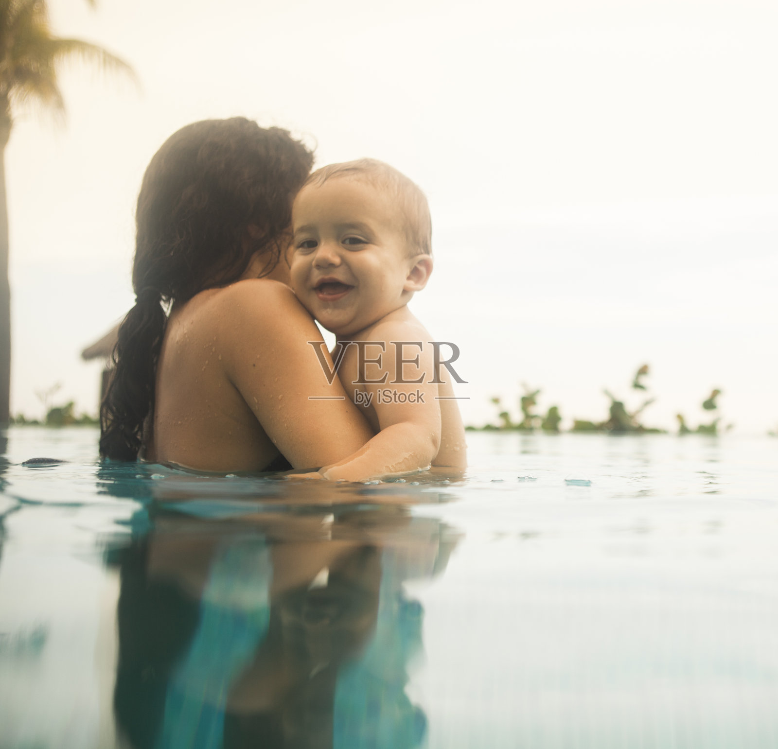 母亲和男婴在游泳池里照片摄影图片