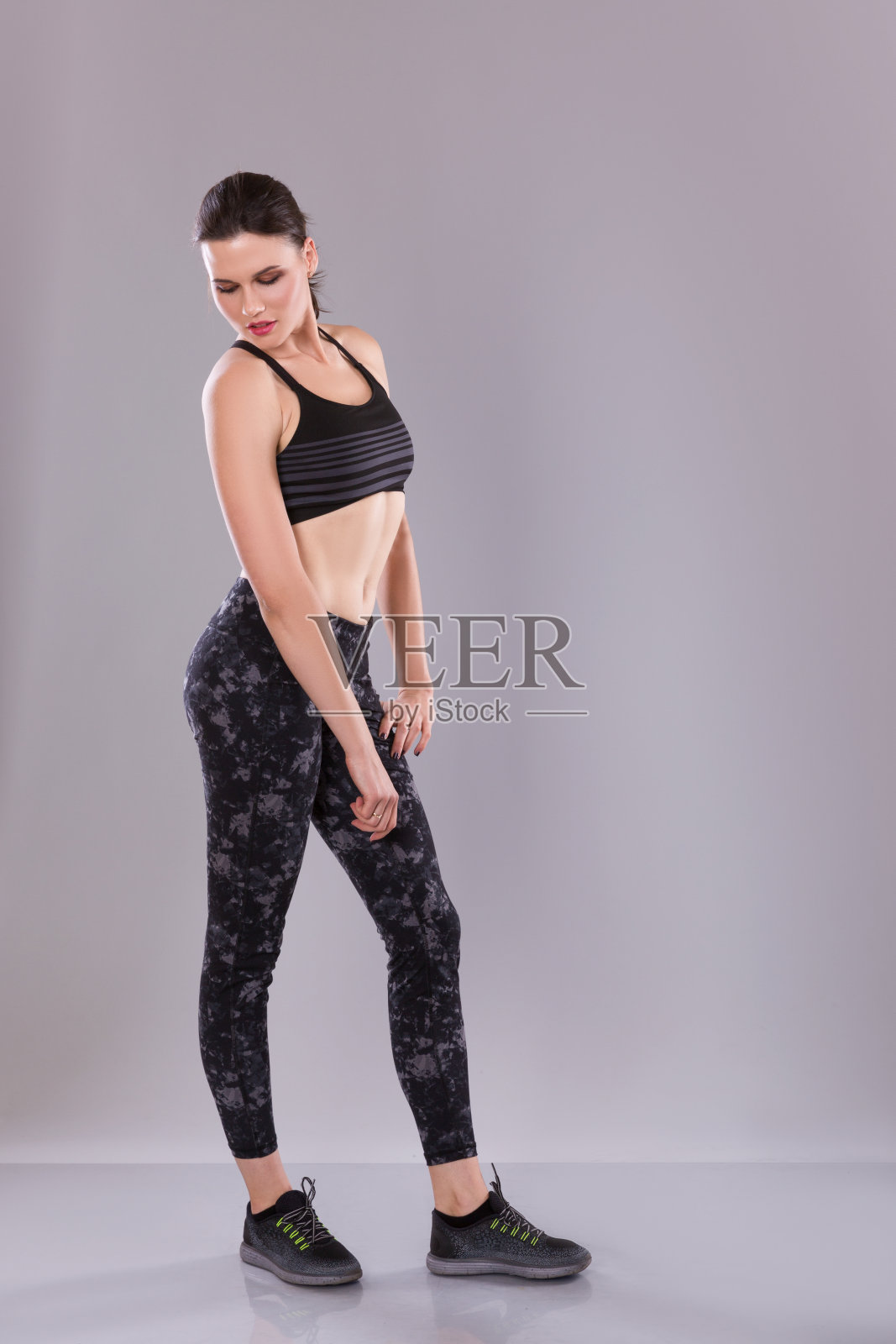 穿着黑色背心和打底裤的健身女性，在摄影棚拍摄。照片摄影图片