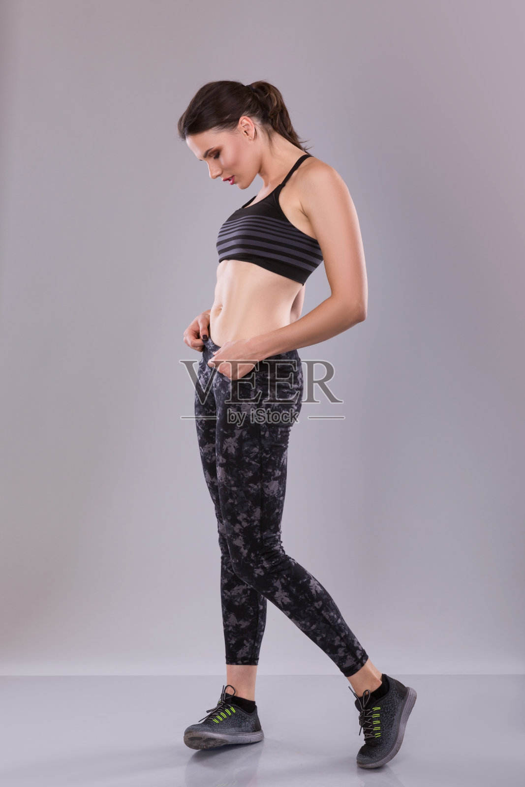 穿着黑色背心和打底裤的健身女性，在摄影棚拍摄。照片摄影图片