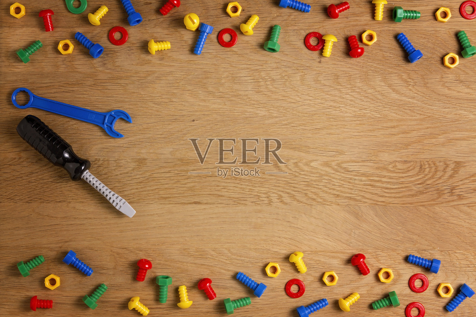 儿童建筑玩具工具:彩色螺丝刀，螺丝和螺母的木制背景。前视图。平的。文本复制空间照片摄影图片