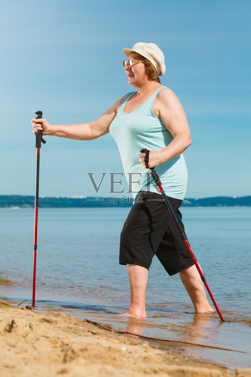 老女人在沙滩上练习北欧步法照片摄影图片