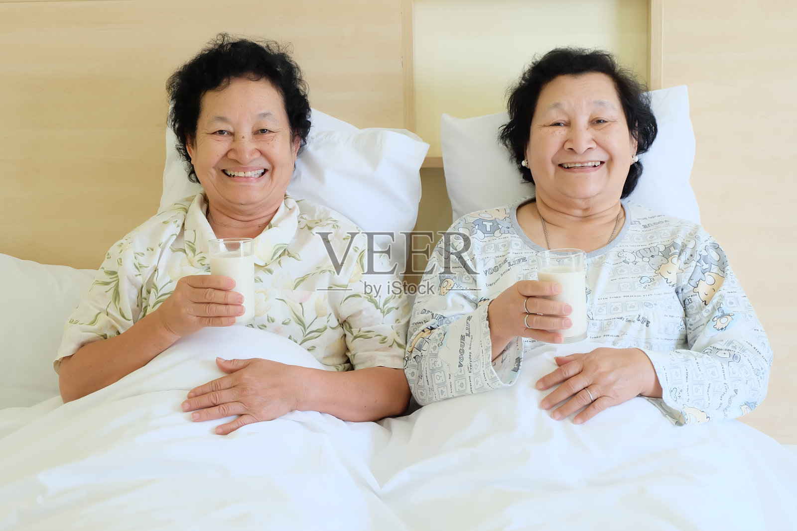 亚洲资深妇女在床上喝牛奶照片摄影图片