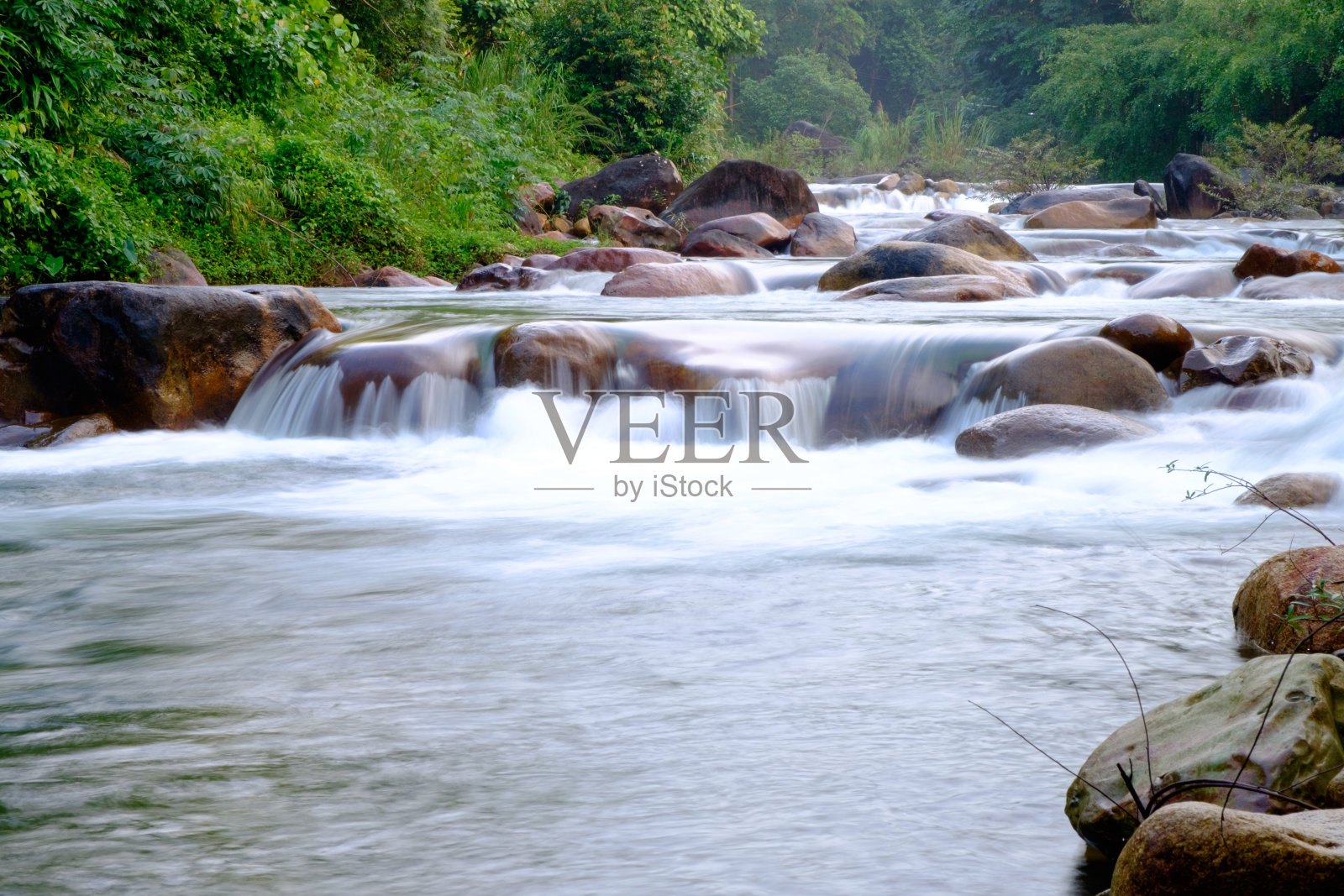 在森林里的岩石间流过的小溪照片摄影图片