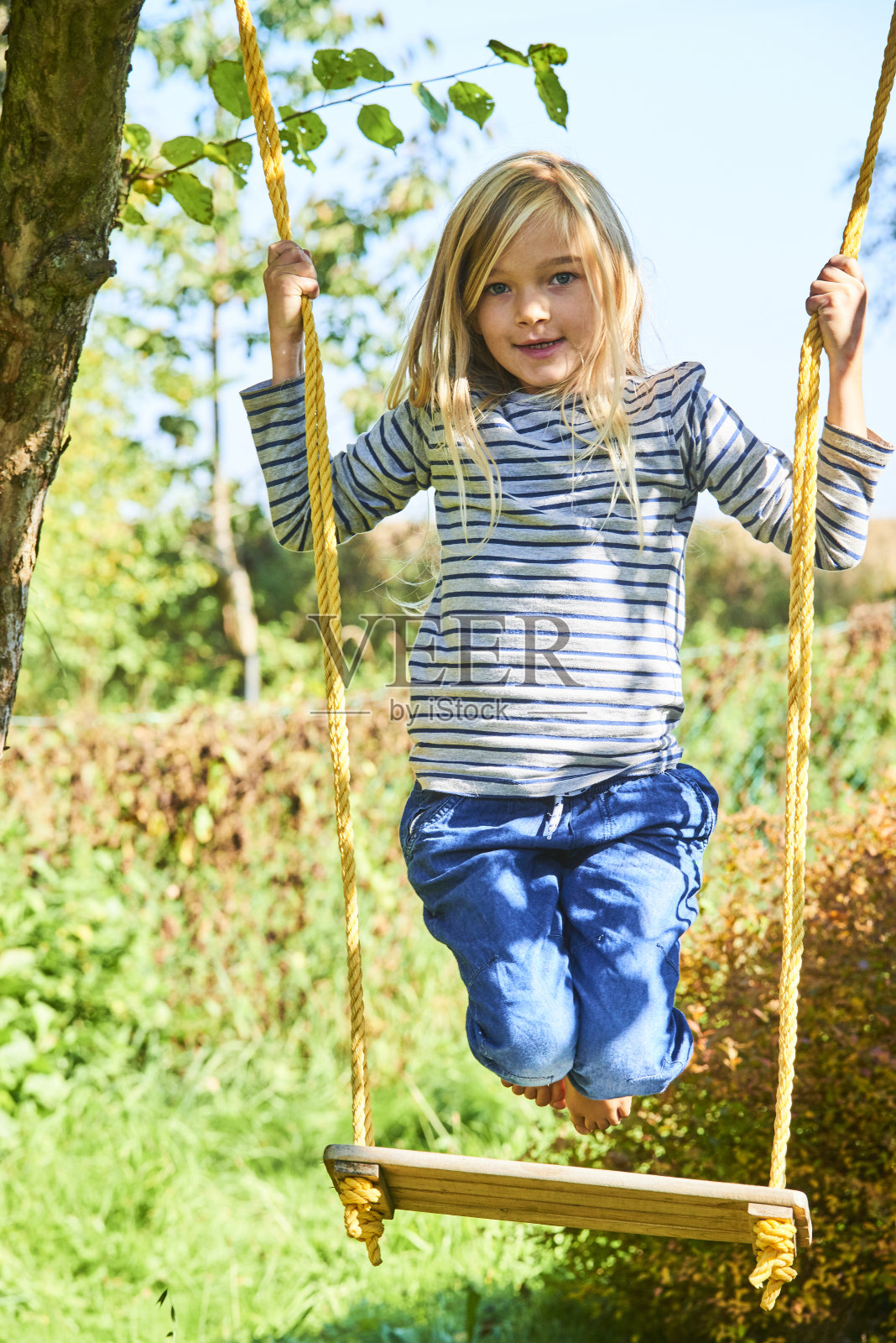 在户外秋千上玩耍的金发小女孩，夏季游乐场照片摄影图片