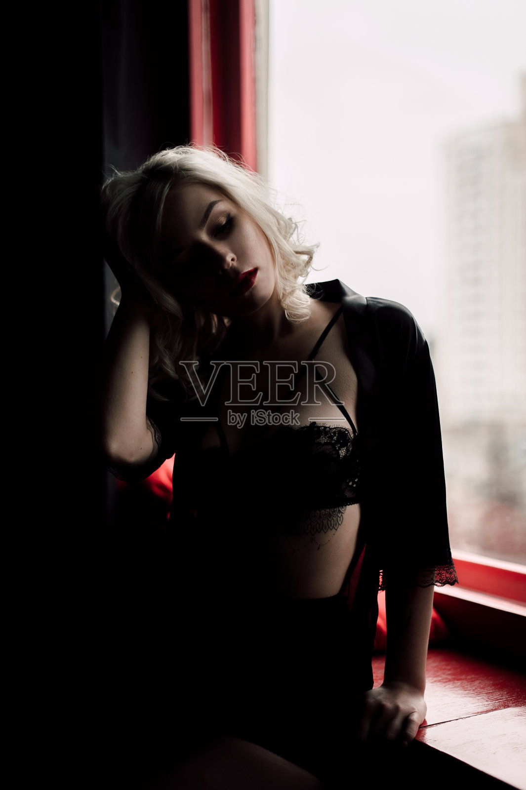 美丽的时尚模特性感和热情的金发女人与红色的嘴唇摆pose靠近窗户穿着黑色性感内衣照片摄影图片