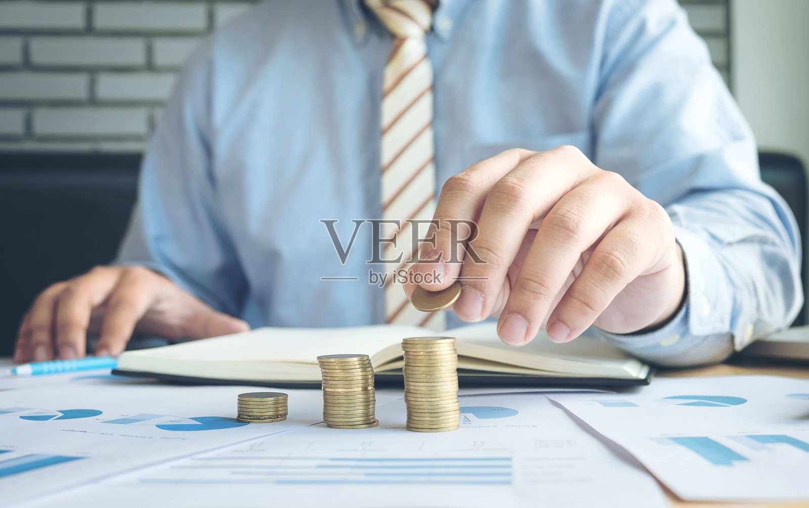 特写的商人手把硬币堆栈上的财务文件，商业概念。照片摄影图片