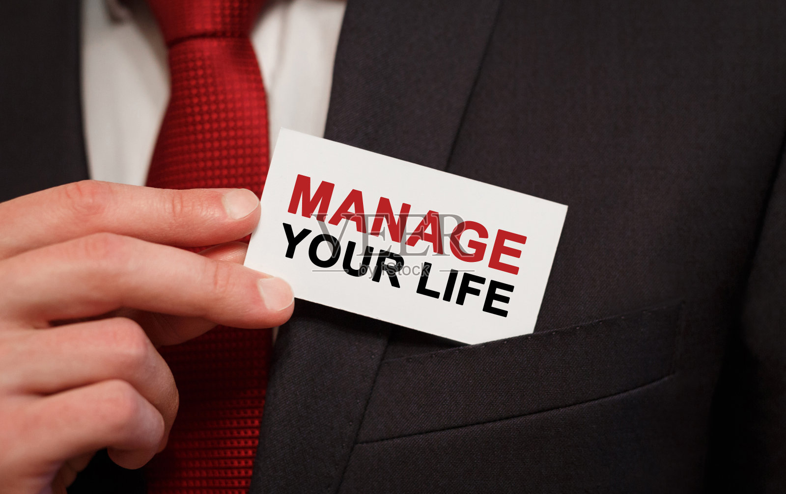 商人把一张写着“管理你的生活”的卡片放在口袋里照片摄影图片