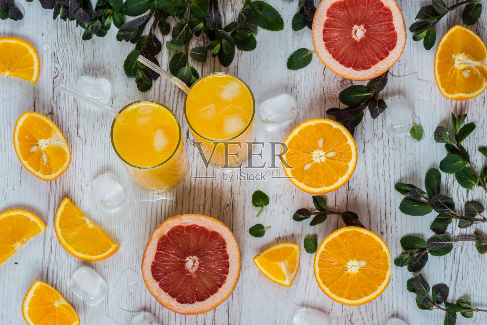 橙汁加冰玻璃杯，靠近柑橘和薄荷，背景为淡木制照片摄影图片