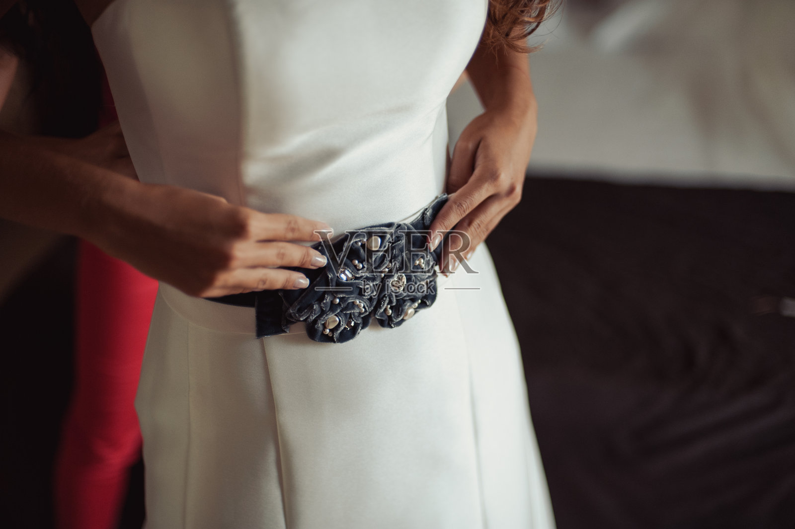 时尚的伴娘礼服帮助佩戴蝴蝶结在新娘的婚纱背后。早上的婚礼。照片摄影图片