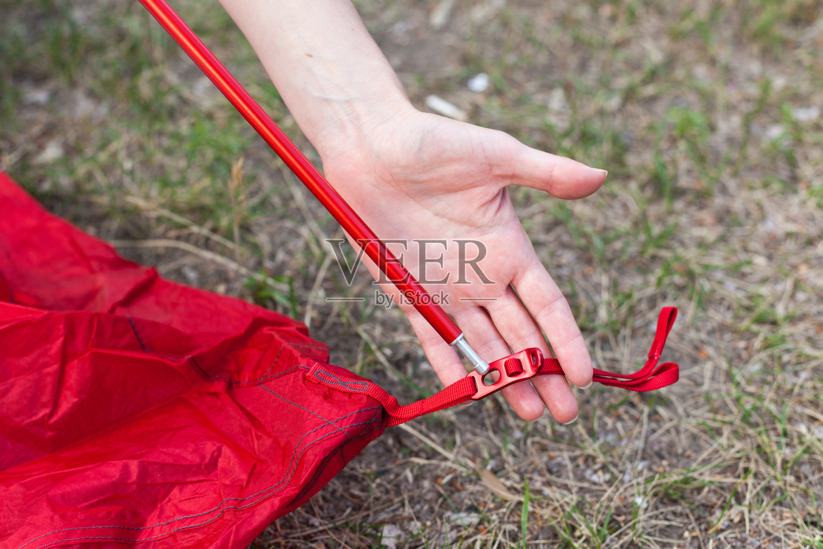 靠近露营帐篷的细节。铝帐篷波兰人。安装帐篷的过程，在户外搭建帐篷。女孩用钩子勾住帐篷的内侧，使其牢固照片摄影图片