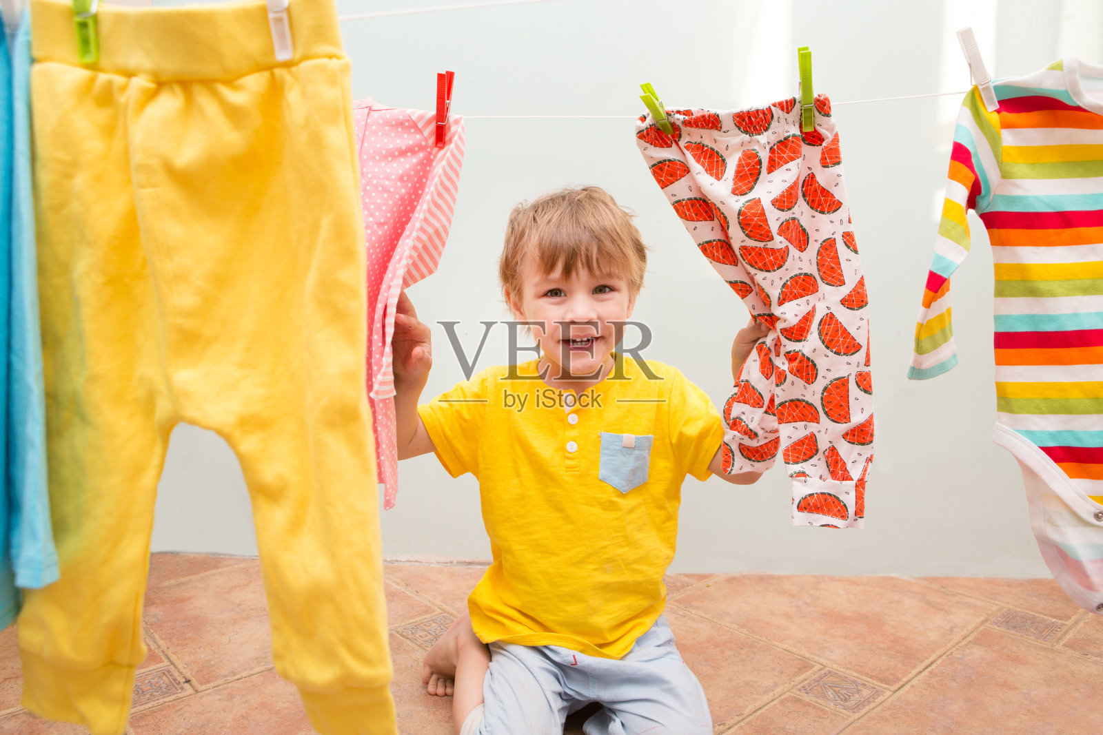 妈妈的助手。孩子开心快乐的小男孩洗衣服，笑在洗衣房照片摄影图片