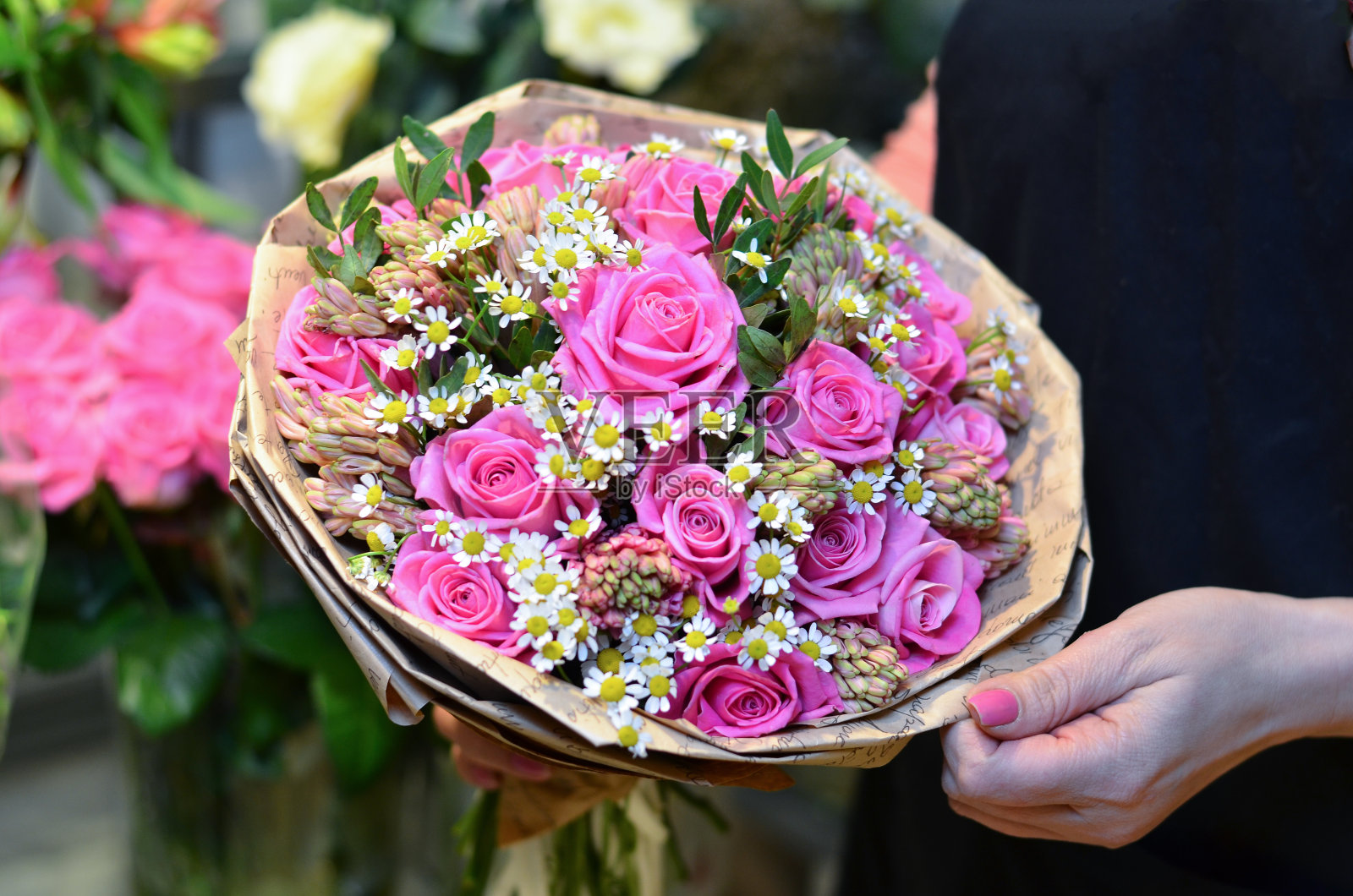 一个女人拿着一束纸包着的玫瑰